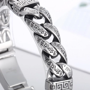 Macro shot of stainless steel Cuban chain bracelet with engraved Buddhist mantras and silver finish