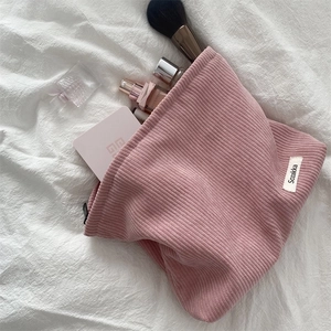 Pink corduroy makeup bag with zipper closure and spacious interior on a white fabric