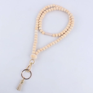 Detail of wooden bead lanyard with heart carving, gold lobster clasp and beige leather tassel