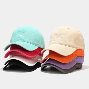 Close-up of assorted cotton baseball caps with embroidered smiley faces in various colors