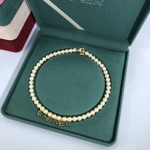 Elegant cream pearl necklace with gold brand pendant in dark green velvet jewelry box