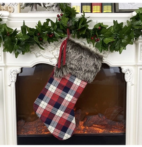 Classic red and green plaid Christmas stocking hanging on a white festive fireplace