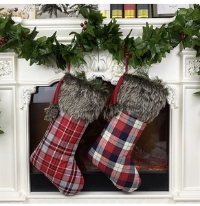 Detail of red and blue plaid Christmas stockings with faux fur trim hanging on fireplace