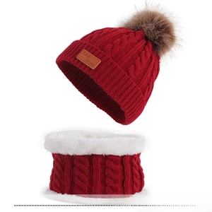 Detail of dark red knit beanie with faux fur pom and fleece-lined winter neck warmer