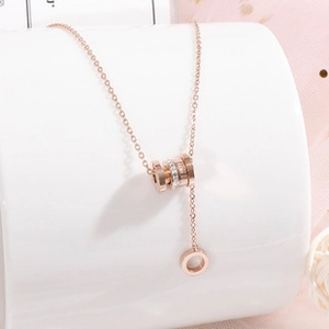 Close-up of rose gold Y-necklace with diamond-encrusted cylinder pendant and fine engraving