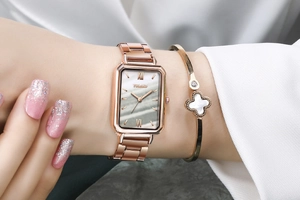 Detail of a square green face watch and clover bracelet set in rose gold finish