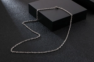 Detailed close-up of a silver stainless steel twist chain necklace on a black background