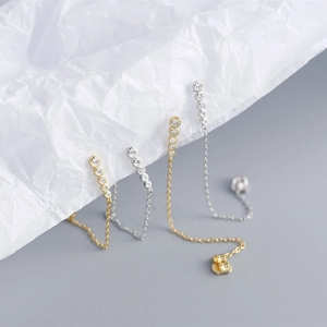 Detail of silver and gold tassel earrings featuring geometric cubic zirconia stones