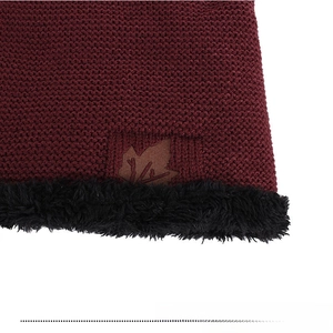 Close-up of wine red knit fabric with maple leaf patch and warm faux fur lining