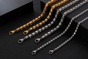 Detailed view of gold and silver flower link necklaces with lobster clasps on dark base