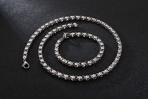 Detailed view of silver stainless steel necklace and bracelet set with floral chain design