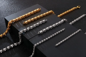 Detail of gold woven and silver floral stainless steel chains on black display