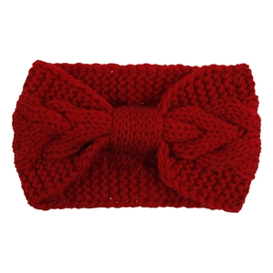 Macro detail of red cable-knit headband featuring twisted knot and thick wool texture