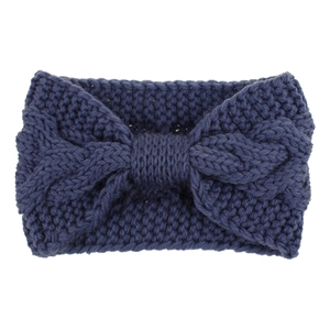 Macro detail of the chunky cable knit texture and bow shape on this dark blue headband