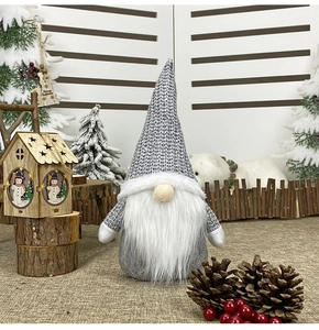 Nordic Christmas gnome plush with gray and white knit hat among snowy pine branches