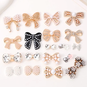 Flat lay macro of diverse bow hair accessories with pearls and rhinestones on beige surface
