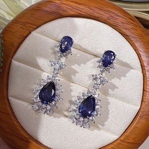 Elegant teardrop blue crystal earrings with diamond halo on wooden jewelry box