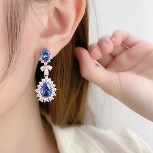 Elegant teardrop blue crystal stud earrings with halo diamonds on model