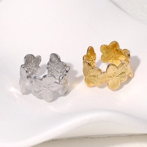 Macro detail of gold and silver floral rings with intricate petal texture on white surface