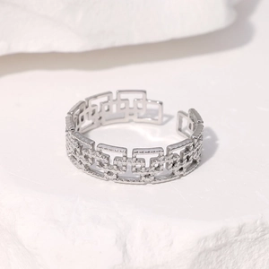 Detail of silver geometric hollow ring on white stone, showing polished interlocking design