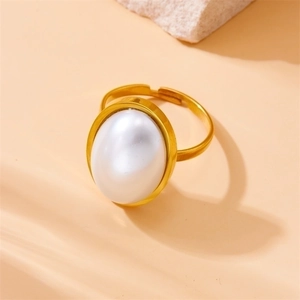 Elegant gold adjustable ring with a large oval white pearl on a warm beige stone background
