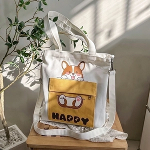 Detail of white canvas tote bag with cartoon corgi print and yellow zip pocket