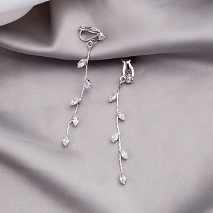 Elegant long leaf tassel earrings with white zircon stones on silk fabric background