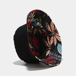 Detail of reversible bucket hat with black canvas exterior and colorful leaf print lining
