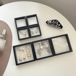 Multiple sizes of black PE film floating jewelry display boxes showing rings and earrings