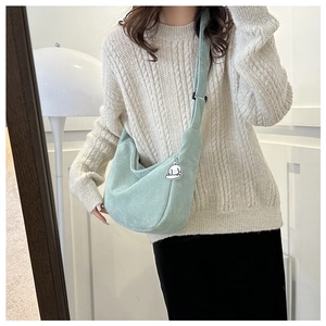 Detail of light green corduroy crossbody bag with soft texture and cartoon charm