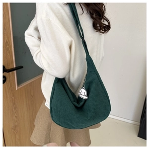 Detail view of a green corduroy hobo bag with a cute sheep charm on a model
