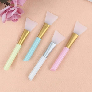 Set of four silicone face mask brushes in assorted colors with metallic tubes on pink backdrop