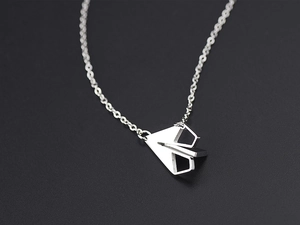 Vue macro détaillée du pendentif avion en papier argenté sur une chaîne en acier titane