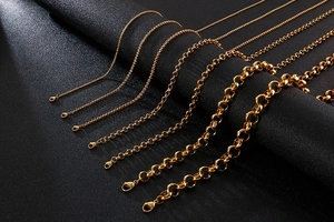 Detail showing various thicknesses of gold stainless steel link chains on dark surface