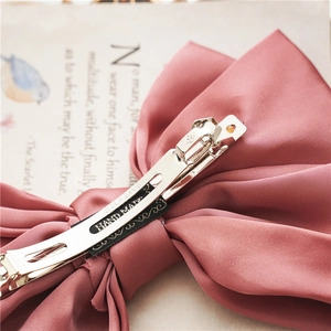 Detailed back view of a pink satin bow hair clip with a Paris metal spring clip