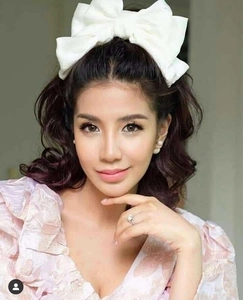 Detail of a large white satin bow hair clip worn by a model in floral puff sleeve dress