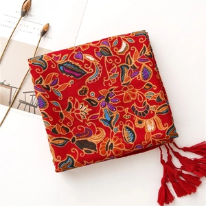Detail of red bohemian cotton linen scarf with ethnic floral patterns and tassel fringe