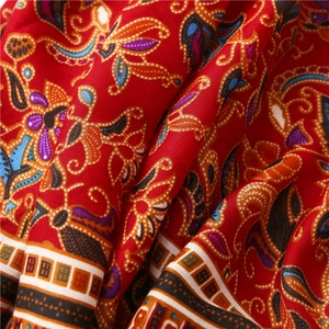 Detailed macro view of bohemian paisley patterns on red cotton linen shawl fabric