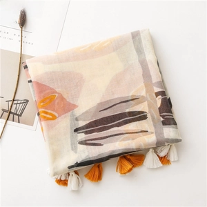 Détail d'écharpe en coton et lin avec imprimés abstraits et pompons à franges orange