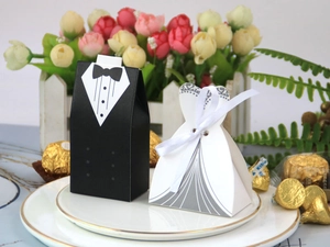 Detail of tuxedo and wedding dress candy boxes placed on a decorative white gold-edged plate