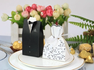 Creative wedding candy boxes featuring black tuxedo and white dress on a ceramic plate