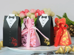 Detail der Smoking- und Blumenkleid-Hochzeitsgastgeschenke mit Schleifen auf Teller