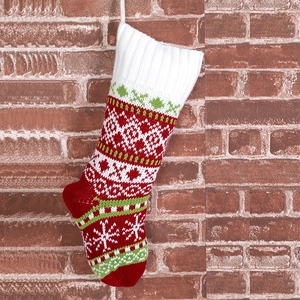 Detailed close-up of knitted Christmas stocking with snowflake patterns on brick background