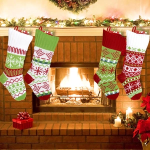Close-up of four knitted Christmas stockings with reindeer and snowflake patterns hanging