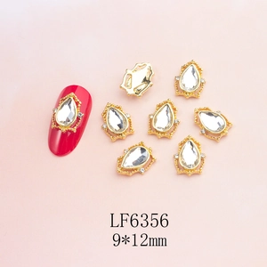 Macro shot of 9x12mm teardrop crystal nail charm with gold frame on red nail art