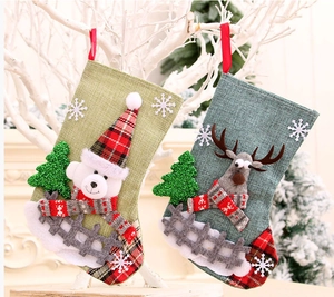 Close-up of linen Christmas stockings with 3D bear and reindeer designs on white branches