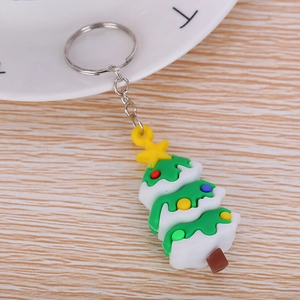 Detailed view of 3D Christmas tree rubber keychain with metal ring on wooden surface
