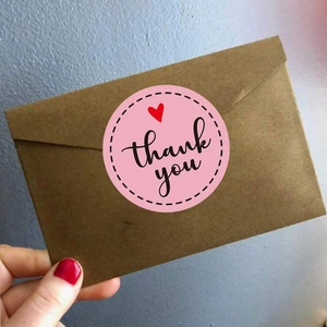 Pink round thank you seal sticker with red heart on brown kraft envelope