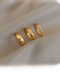 Close-up of three polished 18K gold-plated titanium steel stackable minimalist rings