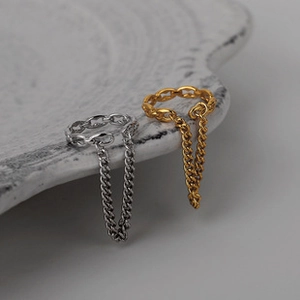 Macro shot of 18K gold and silver chain earrings with long tassel detail on marble